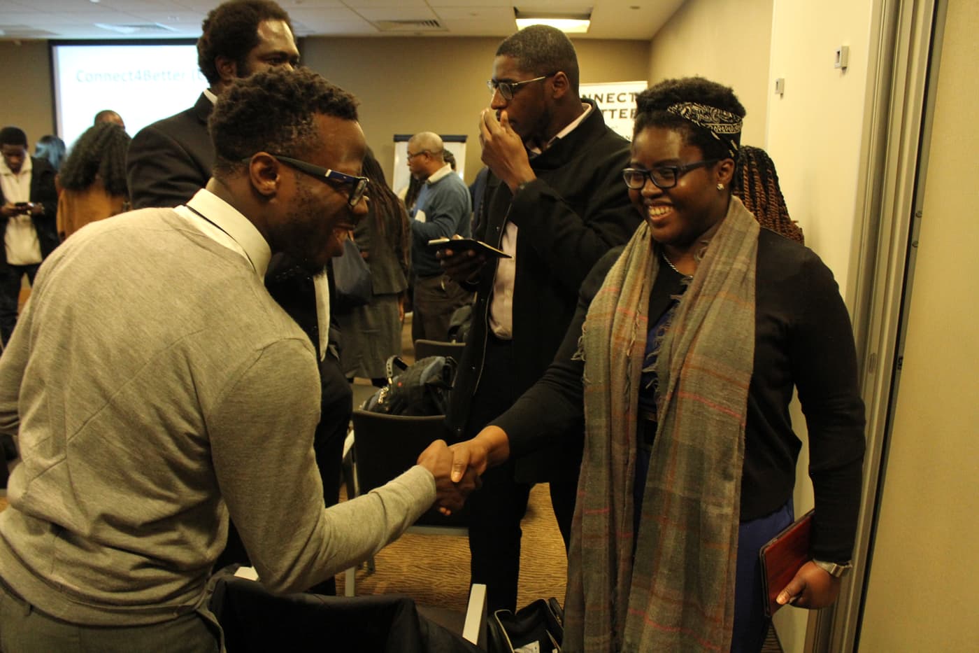 Two attendees shaking hands and laughing after the panel